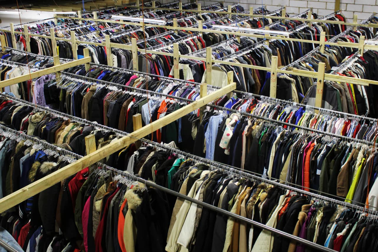 Rows of sorted and tagged second-hand clothing hanging on rails inside the Sait sorting facility
